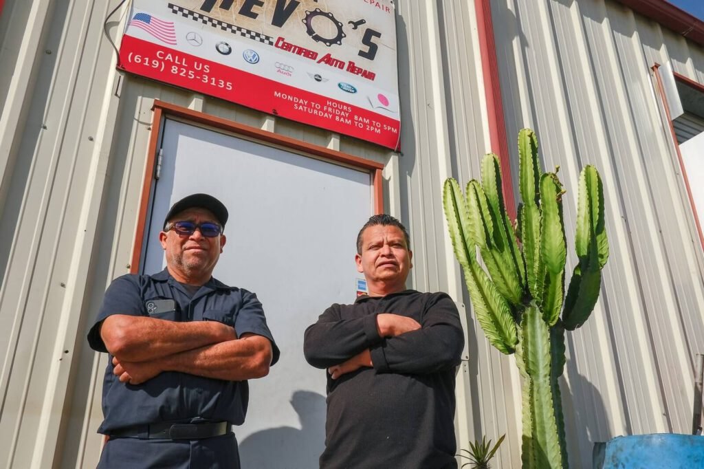 Shop owners stand in front of the shop's entrance.